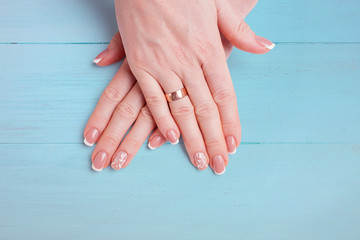 Beautiful hands with modern manicure on a background of blue boards. Closeup