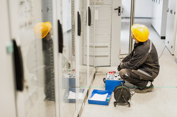 Electrician engineer tests system with relay test set equipment
