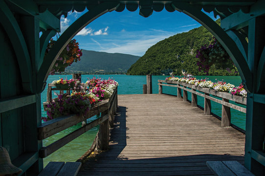 Pier with flowers on the Annecy Lake with blue sky mountains landscape. Near the lovely village of Talloires. Department of Haute-Savoie, southeastern France. 