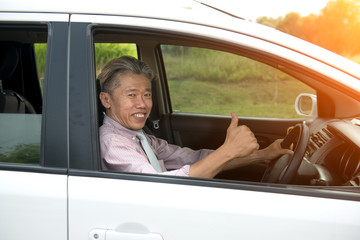 asian senior male driving with thumbs up