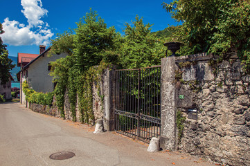 Street and closed gate in a narrow alley with blue sky. At the lovely village of Talloires. Located at the department of Haute-Savoie, southeastern France.