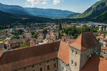 Houses in valley with evergreen mountains and blue sky viewed from the Faverges castle's tower. At...