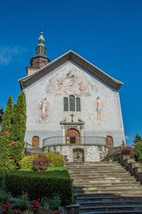 Fototapeta na wymiar Church facade with steeple and paintings. At the historical hamlet of Conflans, near Albertville. Located at the department of Haute-Savoie, southeastern France.
