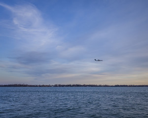 Fototapeta na wymiar Sunset at Lake Ontario . Plane approaching for landing near Billy Bishop Airport in Toronto