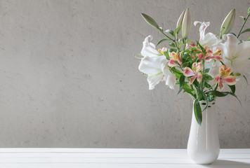 beautiful white lily in vase on background old wall