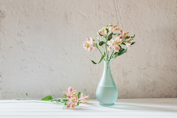 Fototapeta na wymiar Alstroemeria in vase on grunge white background
