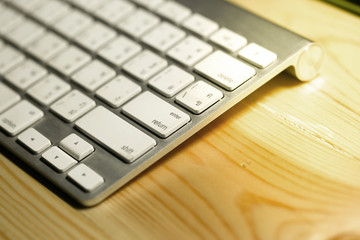 Close up the keyboard on the desk. Light from the lamp.