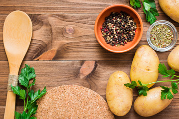 Fresh potatoes, greens and spices on a wooden background. Space for the inscription. Top View