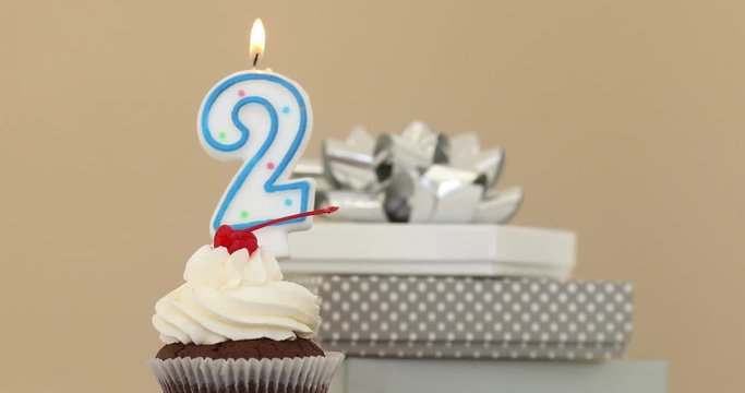 Number 2 candle in a cupcake against a pastel background blow out at the end