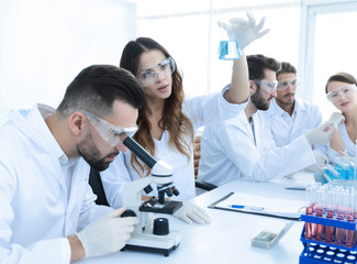 Scientists examining attentively pipette with blue fluid in laboratory
