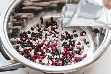 Beans for cooking are poured with water. Colored grains in a pan