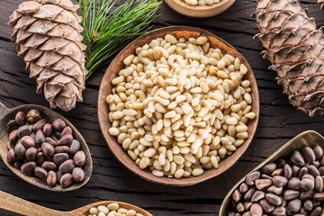 Pine nuts in the bowl and pine nut cones on the wooden table. Organic food.