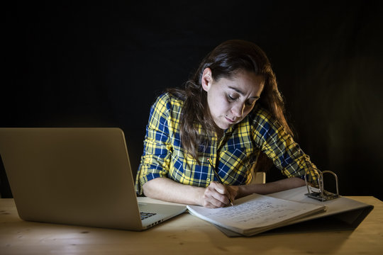 Overworked And Tired Student Woman Studying Late At Night On Black Background.