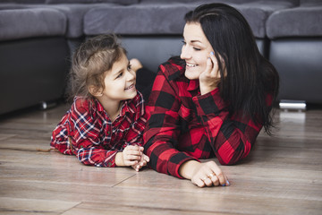 Beautiful happy family mother and daughter smiling together at home lying on the wooden floor in...