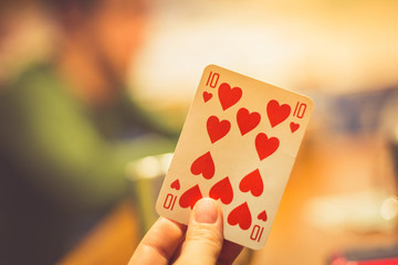 Playing card in the hands of a woman on the background of an opponent on the card game. Close up. Toned.