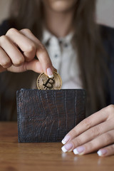 Obraz premium Successfully woman put a Bitcoin into wallet. Crypto coin saving.