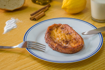 Torrija. It consists of a slice of bread that is soaked in milk or wine and, after being coated in egg, fried in a pan with oil. It is sweetened with sugar and is flavored with cinnamon.
