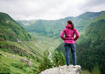 Naklejka premium Rear view shot of a woman looking away standing on top of a rock in the mountains copyspace Romania Europe travel travelling freedom happiness tourism achievement active living.