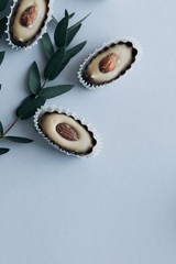 Composition of delicious praline sweets with almonds and green twigs on blue background