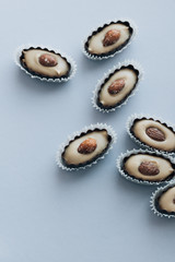 Flat lay of delicious praline sweets with almonds on blue background 