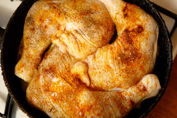 Raw chicken legs with spices on it. In a frying pan.