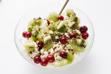 Delicious cottage cheese with kiwi pieces and cranberries in bowl on white background, closeup, healthy breakfast