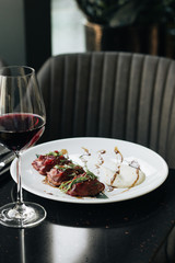 Wineglass with red wine and table with meal on black table