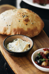 Homemade fresh bread, hummus and olives on wooden board