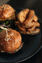 Delicious burgers with lettuce on black plate in cafe