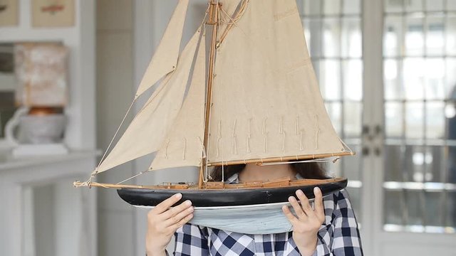 A happy young woman is holding a model of a sailing ship