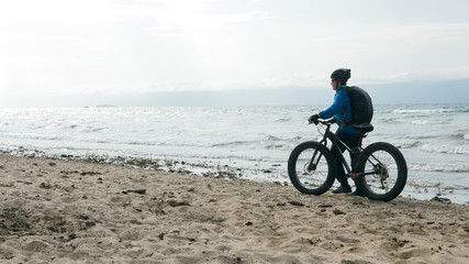 Obraz premium Fat bike also called fatbike or fat-tire bike in summer driving on the beach. The guy is going straight on the beach. On the sand on such a bike ride is not difficult.