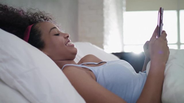 Teen Using Mobile Telephone For Chat In Bed At Home