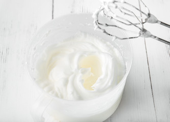 Cooking in the kitchen: whipped whites in a whisk can on a white wooden background, top view