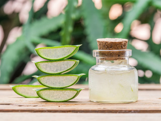 Fresh aloe leaves and aloe gel in the cosmetic jar on wooden table.