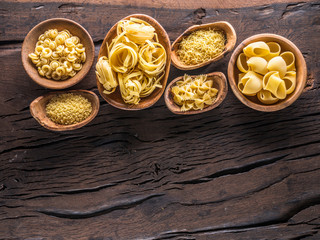 Fototapeta na wymiar Different pasta types in wooden bowls on the table. Top view.