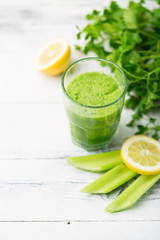 Green cocktail smoothie parsley celery lemon lime slices, healthy drink ingredients, glass of beverage on white wooden table, detox diet clean eating, with vegetables on table