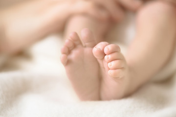 Obraz na płótnie Canvas Newborn baby feet on creamy blanket. Mom and her child. Maternity, family, birth concept. Copy space for your text.