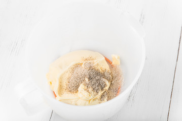 Cream cream for the cake: beaten butter with sugar and vanilla in a whisk can on a white wooden table