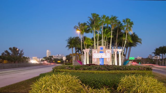 Welcome to Miami Beach FL Signage Traffic Timelapse with Moving Lights from Passing Cars in front of a Vibrant Blue South Florida Sky at Dusk