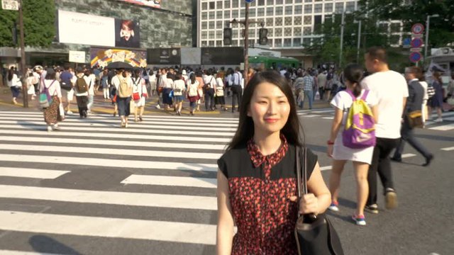 Attractive Japanese woman walking across the famous Shibuya Crossing in Tokyo.
