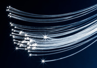 Bundle of optical fibers with lights in the ends. Blue background.