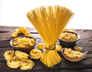 Different pasta types on wooden table. White background.