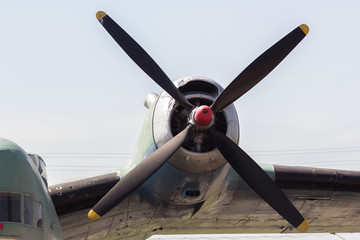 Close up of airplane turboprop engine with propeller, parts of aircraft fuselage, wings and tail on the sky background