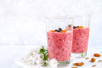 Blueberry smoothies of berries, banana and almonds in glasses with cocktail tubes on a white wooden board.