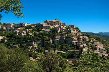 Fototapeta na wymiar Panoramic view of the village of Gordes on top of a hill and under sunny blue sky. Located in the Vaucluse department, Provence region, in southeastern France