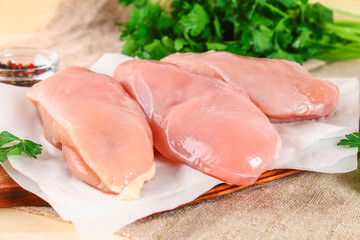 raw chicken fillets on wooden cutting board.