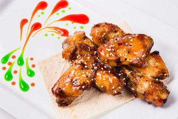 Fried chicken wings with sauce on a white plate (close)