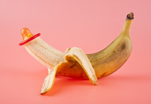 ripe banana and red condom on a pink background