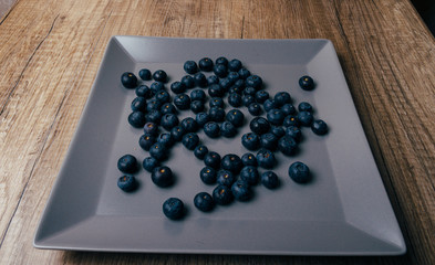 large, fresh blueberries lie on a gray plate, close-up