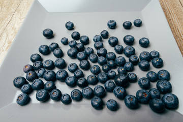 large, fresh blueberries lie on a gray plate, close-up